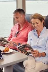 couple sitting and reading magazine in club class onboard condor liberation