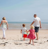 a family walking along the golden sands on a beach in jersey