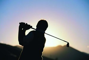 man swinging golf club on a golf course in the uk 