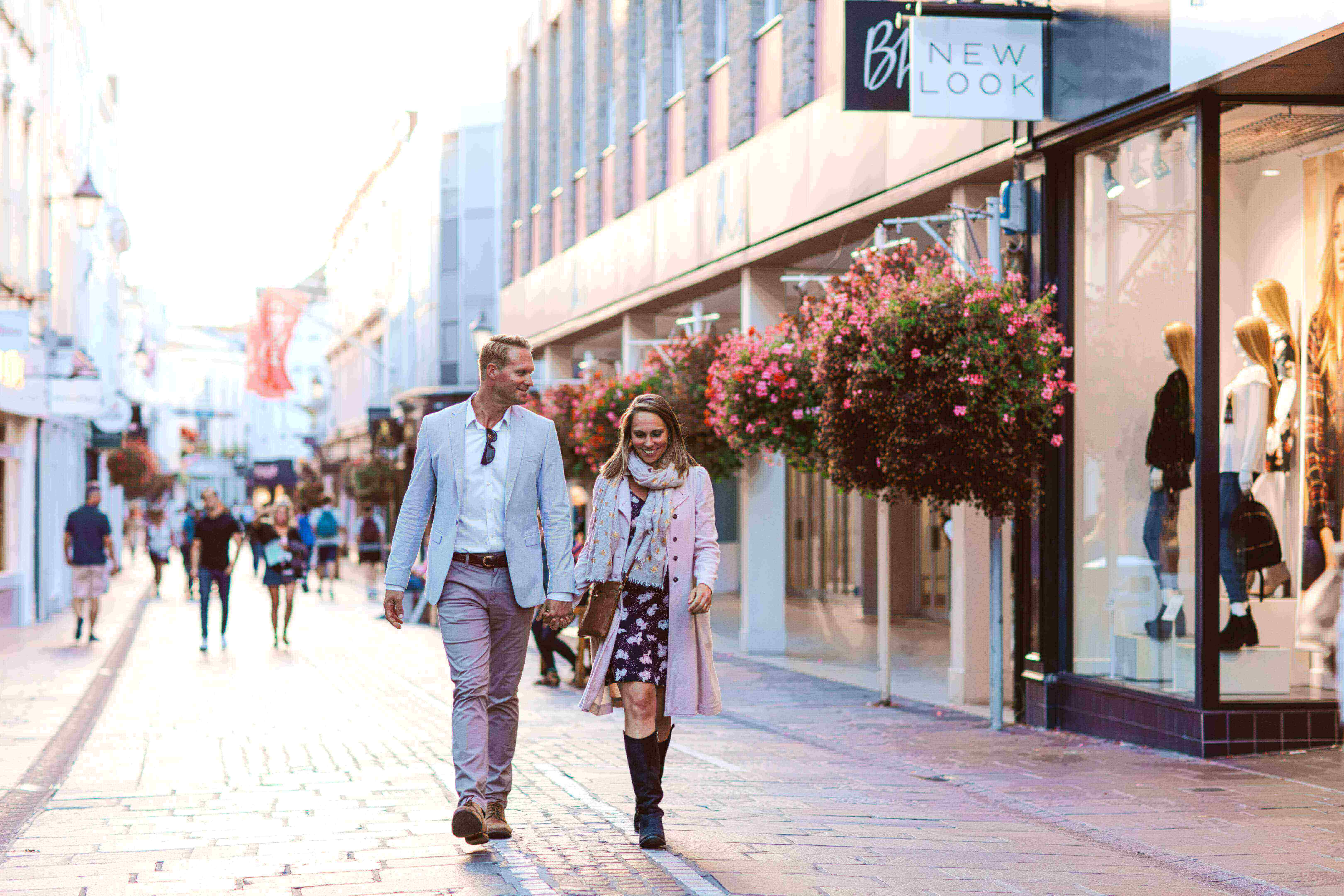 a couple walking past shops in st helier jersey channel islands