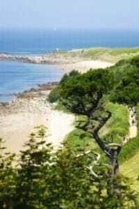 guernsey beach with grassy hills, white sand and blue sky