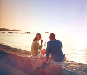 couple sitting on rock looking over guernsey sea channel islands