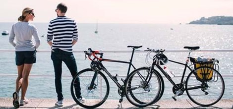 couple with their bicycles looking over sea in jersey channel islands