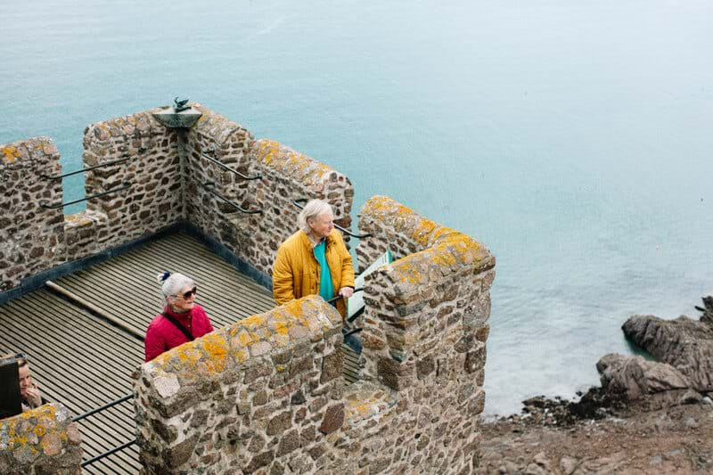 couple looking over view at mont orgueil jersey channel islands