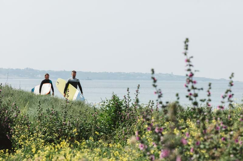 two surfers walking in st ouen's bay jersey