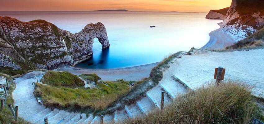 view with clifftop and golden sands with blue sea at durdle door dorset
