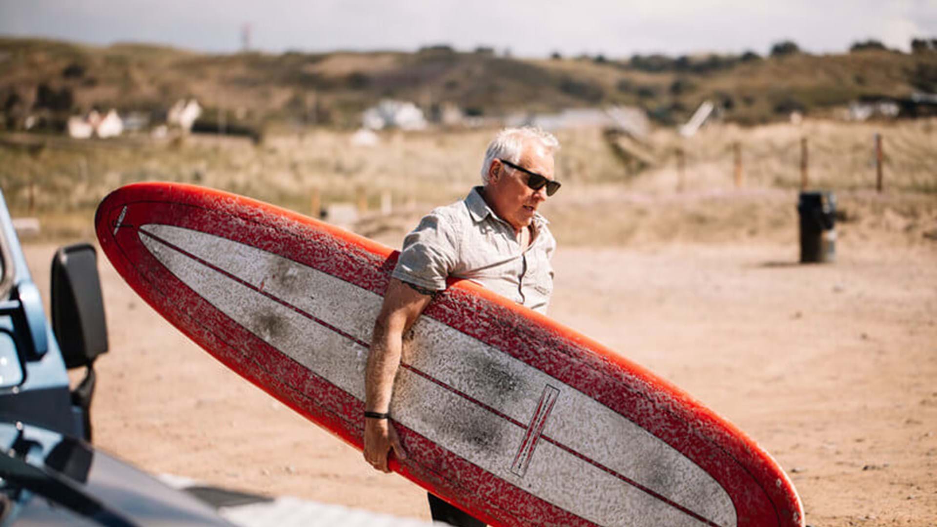 man-walking-with-surfboard-jersey-channel-islands